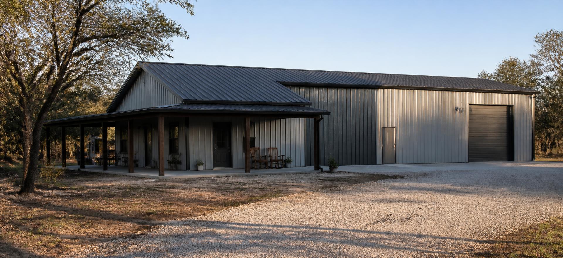 Concept photograph of a light grey steel barndominium with a covered porch on the living end and a large overhead door on the shop end; example configuration, not a real project.