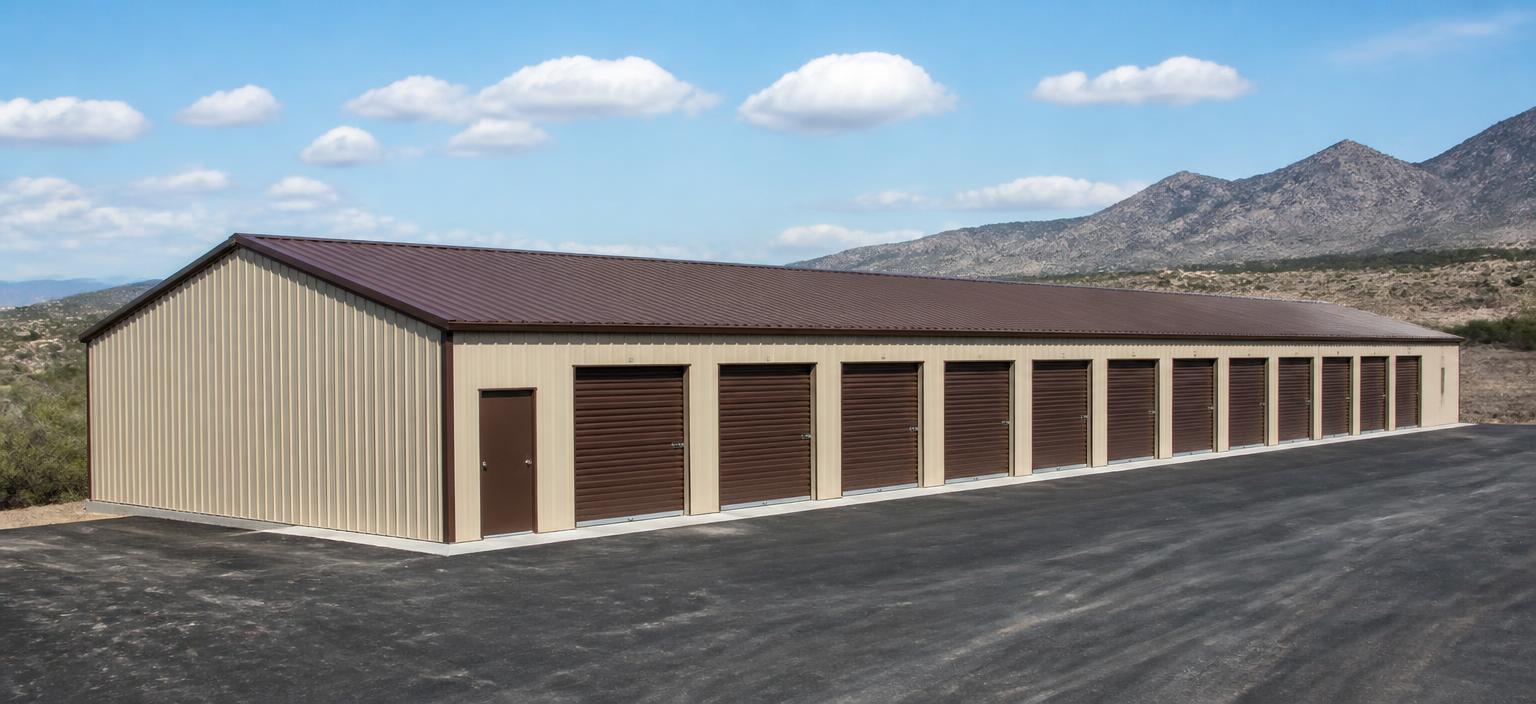 Illustrative steel building configuration showing a long sand-coloured self-storage building with a run of brown roll-up doors, one personnel door and a brown low-slope gable roof beside an asphalt drive aisle.