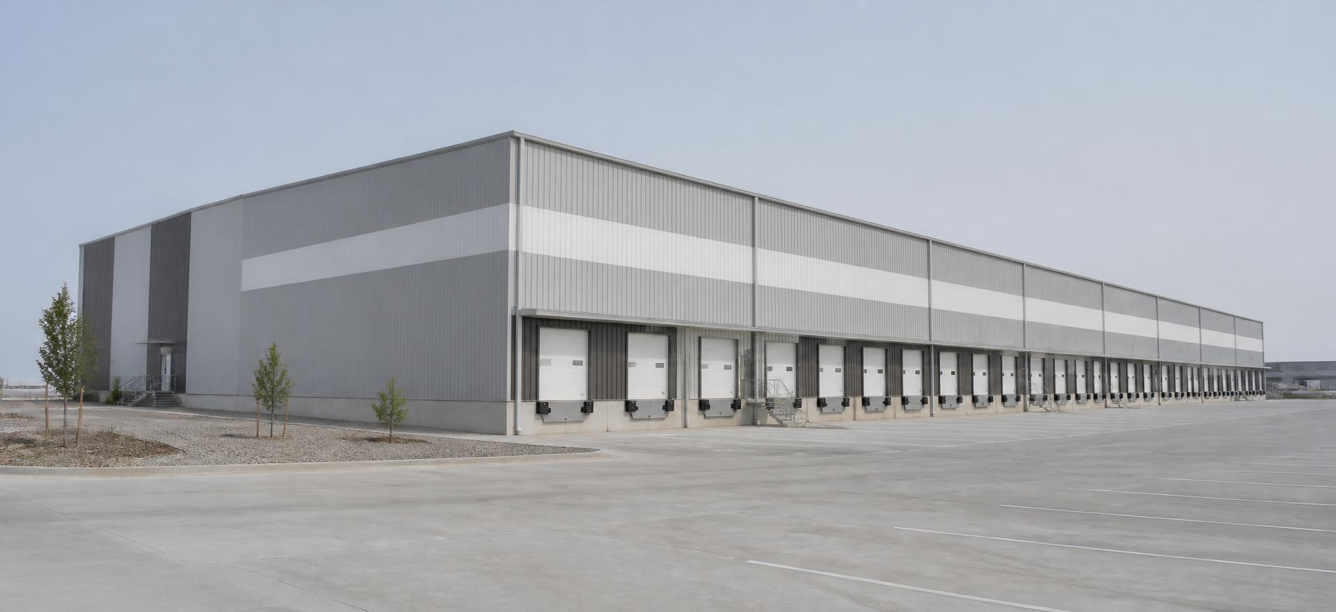 Concept photograph of a long grey rigid-frame steel distribution warehouse with a row of dock doors and levelers on a concrete truck court; example configuration, not a real project.