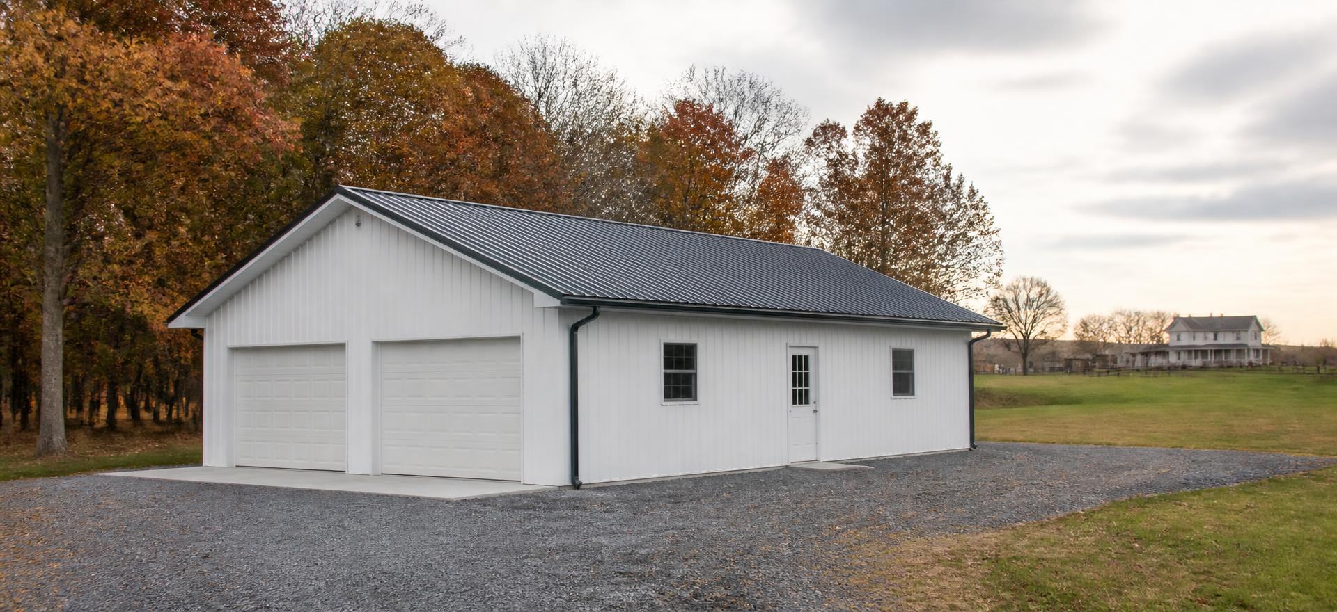 Concept photograph of a 30 by 40 foot white post-frame garage with a charcoal gable metal roof, two overhead doors, a walk door and two small windows on a gravel drive; illustrative configuration, not a real project.