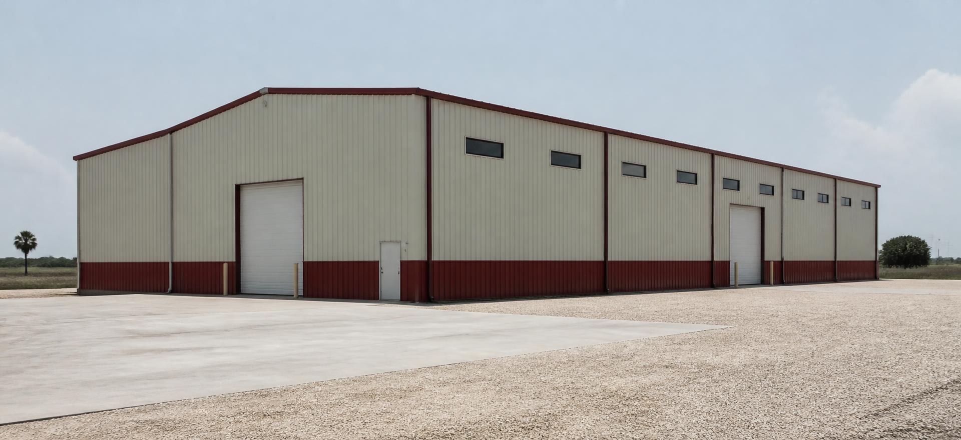 Concept photograph of a tall off-white steel warehouse with a red base wainscot, two drive-in doors and small clerestory windows on a concrete apron; example configuration, not a real project.