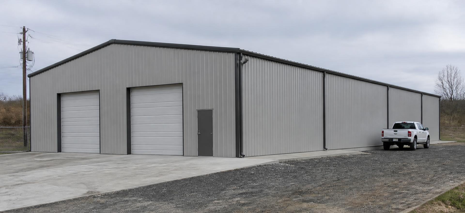 Concept photograph of a 60 by 120 foot gray rigid-frame steel commercial building with two overhead loading doors on a concrete apron; example configuration, not a real project.