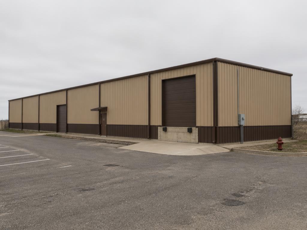 Concept photograph of a 50 by 80 foot tan steel warehouse with a brown wainscot, roll-up dock door and asphalt parking; example configuration, not a real project.