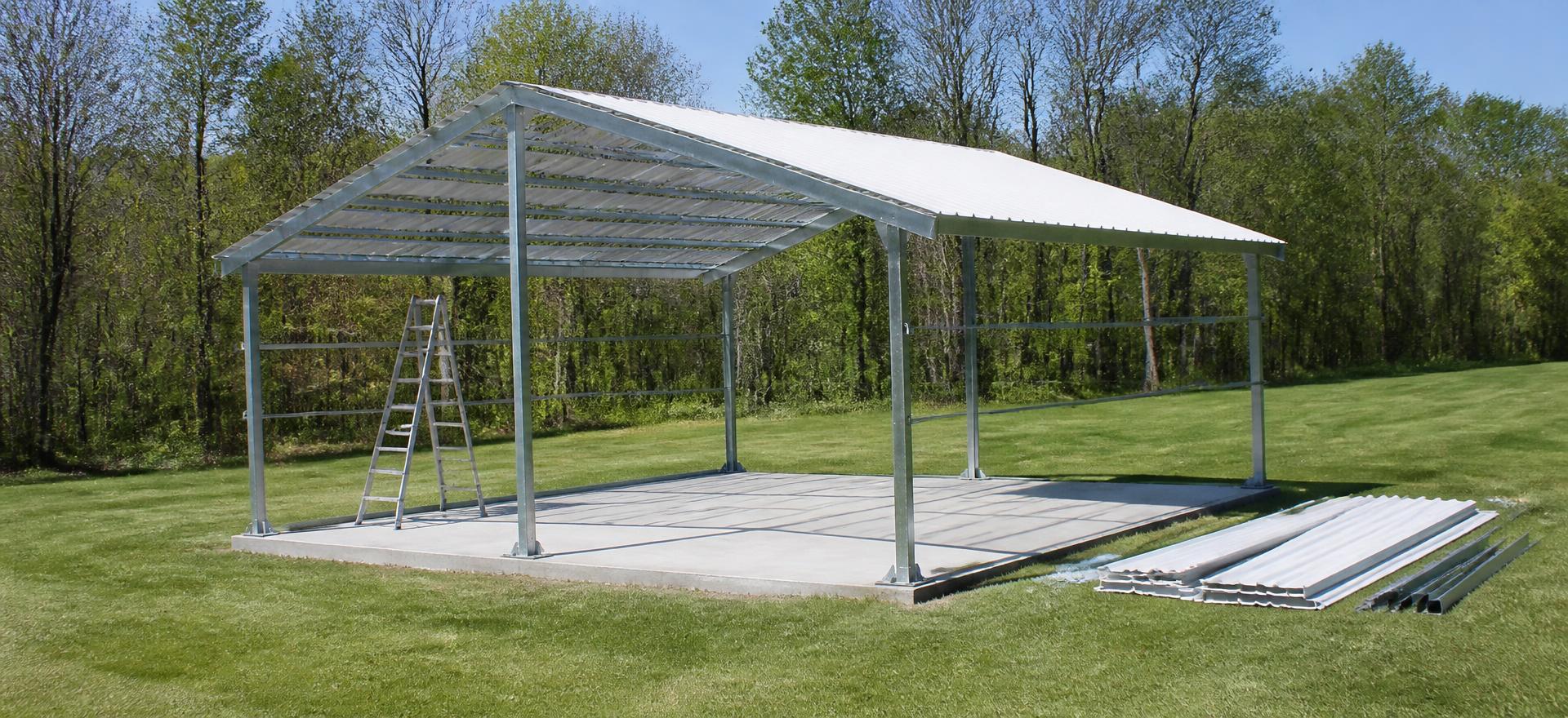 Concept photograph of a 20 by 20 foot bolt-together steel building kit part-way through assembly, with an erected galvanized tube frame on a concrete slab, roof panels half installed and remaining panels stacked on the grass; illustrative configuration, not a real project.